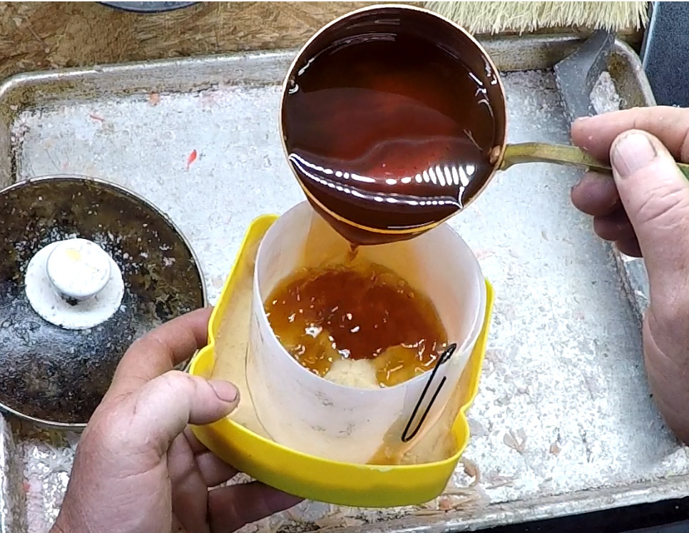 Molten wax being poured into a paw impression